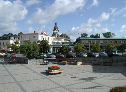 Torg, blommor, kyrktorn, träd, parkerade bilar, centrala byggnader