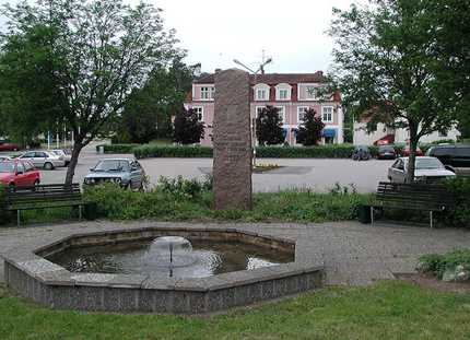 Fontaine, monument, voitures en stationnement, maison rose, église