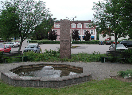 Fountain, monument, parked cars, pink houses, trees